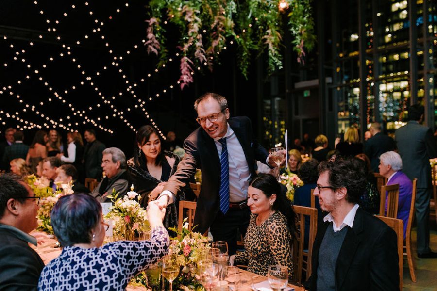 Guests happily greet one another at an outdoor evening dinner behind the ICA.