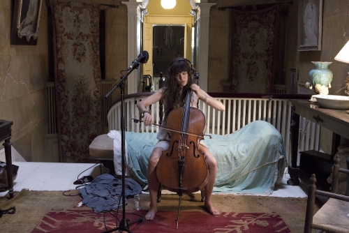A still from The Visitors with a woman playinge cello.
