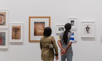 Two visitors from behind viewing framed photographs on the gallery wall.