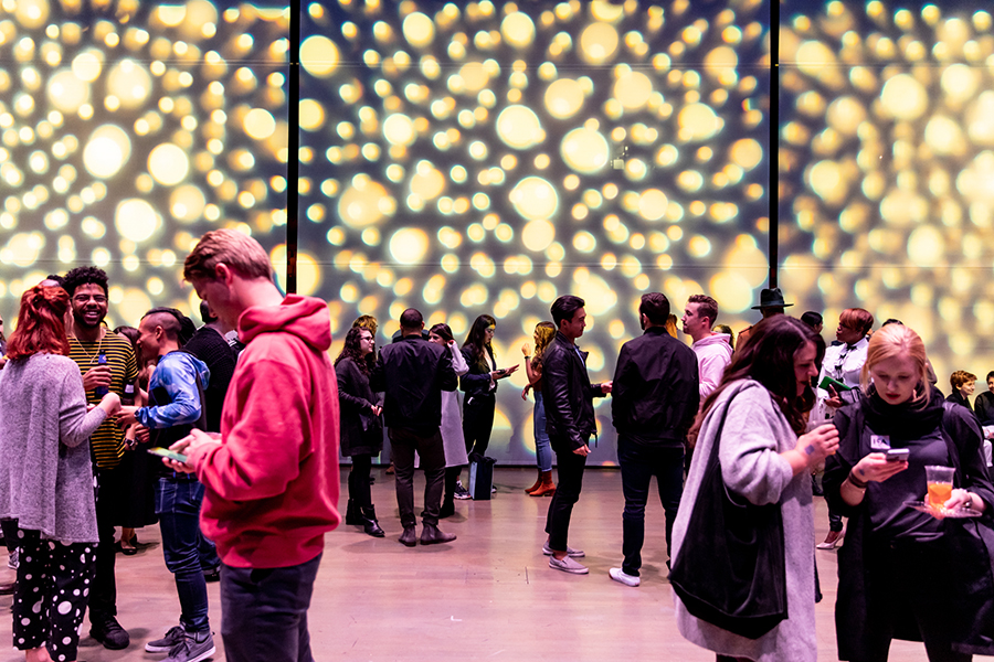 People drinking and hanging out in the ICA theater with yellow lights. 