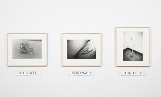 Three black-and-white photographs each depict an overturned mobility object: a wheelchair, walker, and cane. Plaques under the images read "Hot Butt,", "Stud Walk,", and "Third Leg."