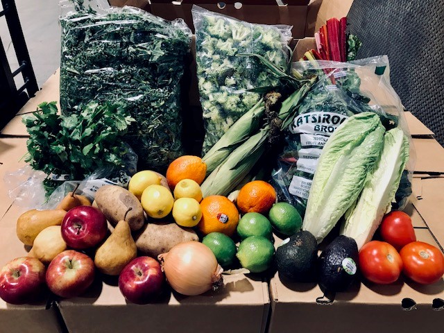 Fresh fruit and vegetable produce on top of shipping boxes.