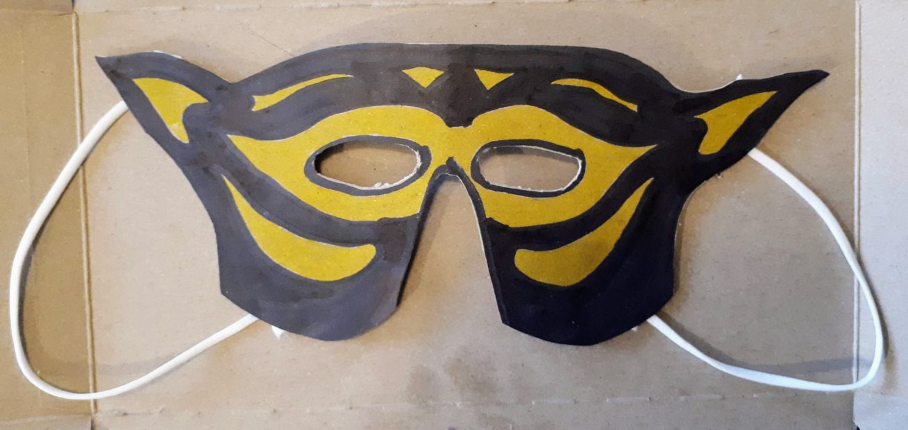 A black and yellow costume mask made from paper