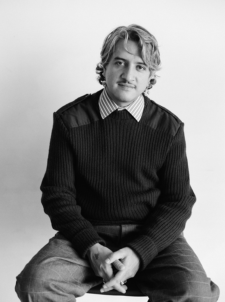 Black and white photo portrait of artist Raúl de Nieves seated in a dark sweater