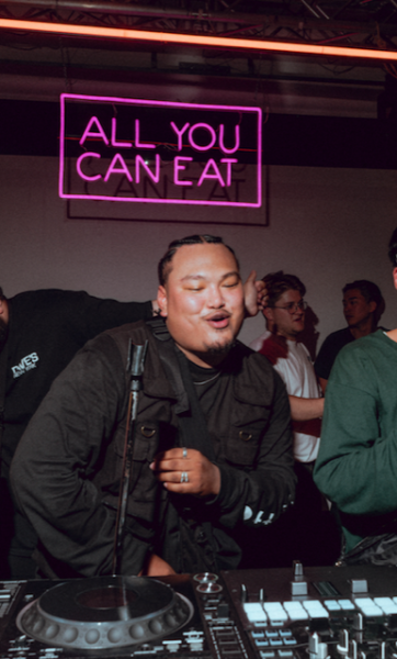 DJ Yung Towfu in front of a neon sign reading 