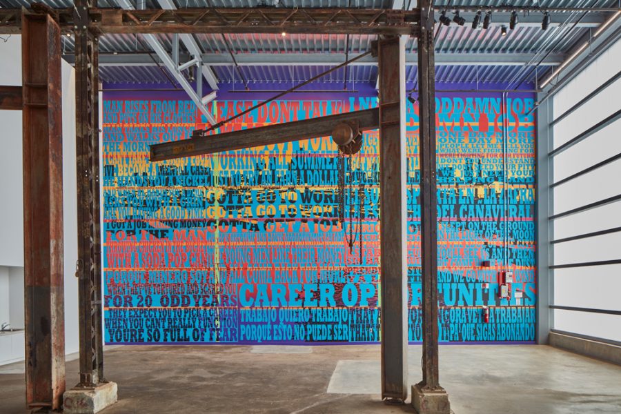 Brightly painted wall with text and images overlaid and metal industrial beams in front