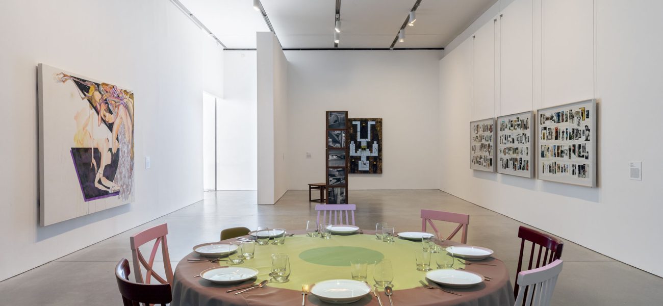 Gallery with round table setting and works on wall and sculptural works