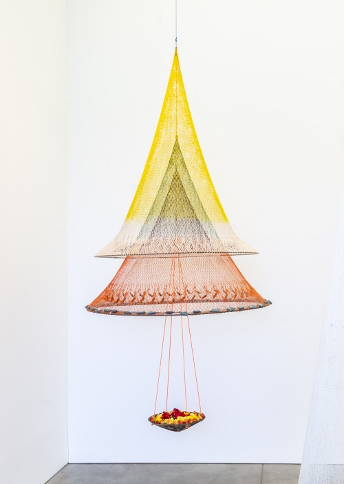 A hanging sculpture made of fishing nets suspended to create an inverse conical shape. 