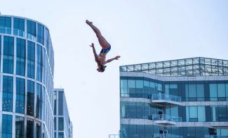 Person diving through air among Seaport skyline