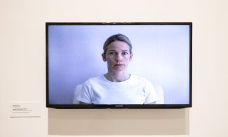 A TV screen displaying a woman in a white shirt against a white background