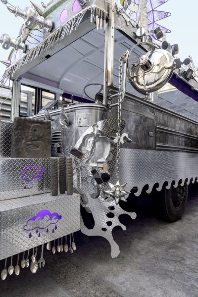 Metal bus with image of a rain cloud at the front, spoons hanging off the front of the bus
