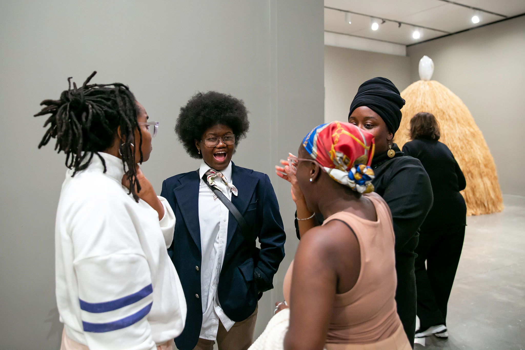 A group of Black visitors talking while in the Simone Leigh exhibition