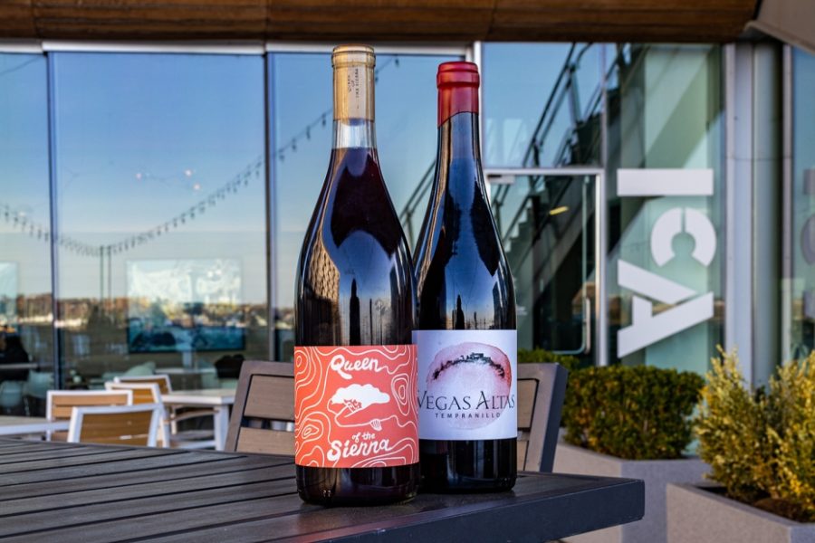 Two red wine bottles on a table outside of the ICA