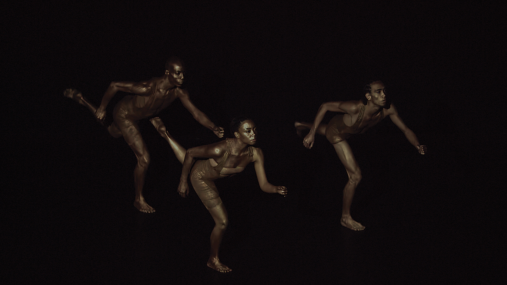 Dark performance photo of three Black performers in brown outfits running