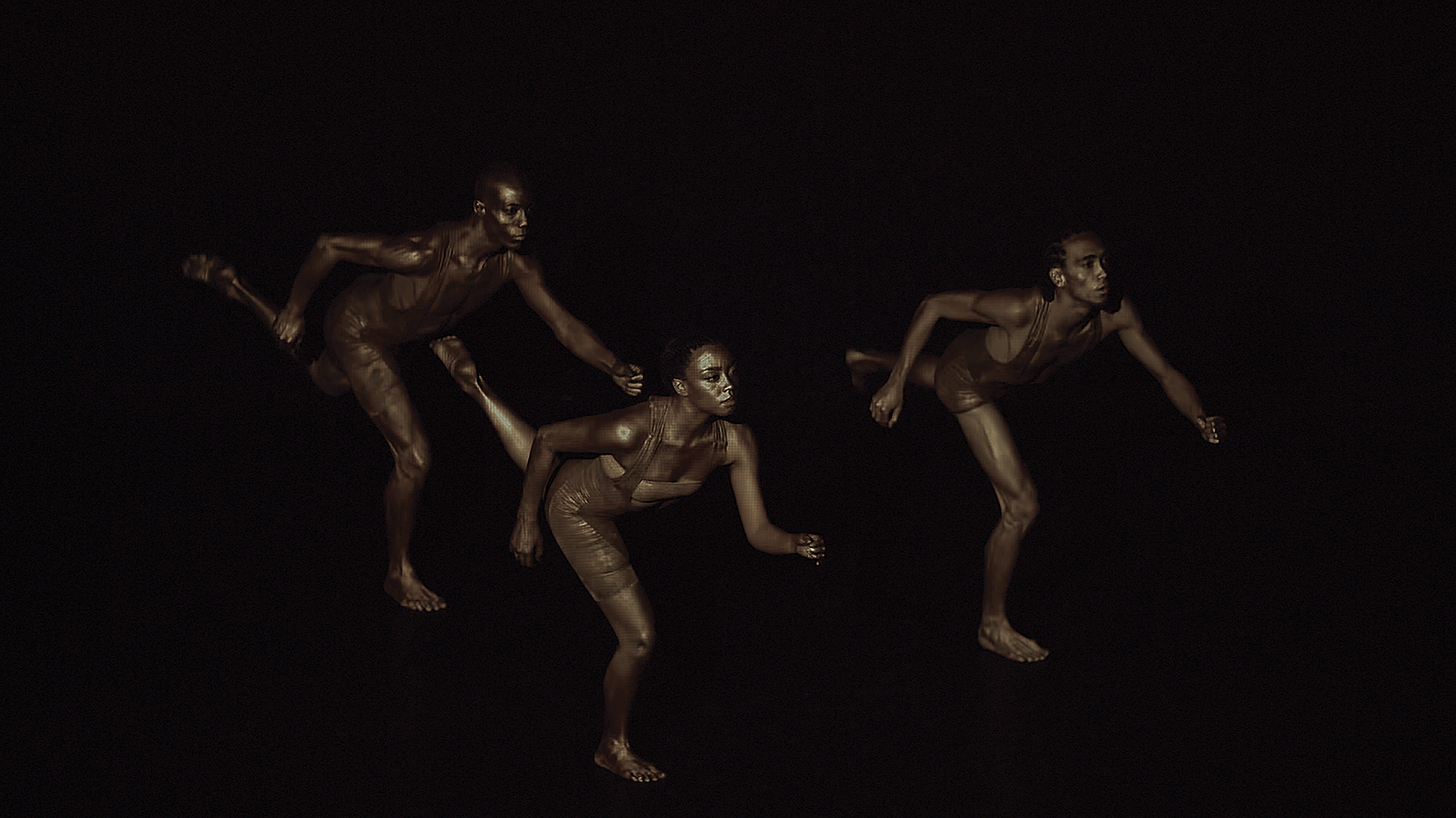 Dark performance photo of three Black performers in brown outfits running