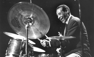 A black and white image of Max Roach playing drums