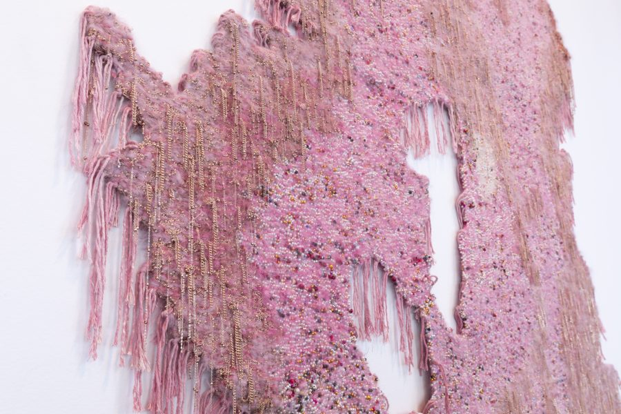 Fringed pink beading with delicate gold chains hanging on a wall