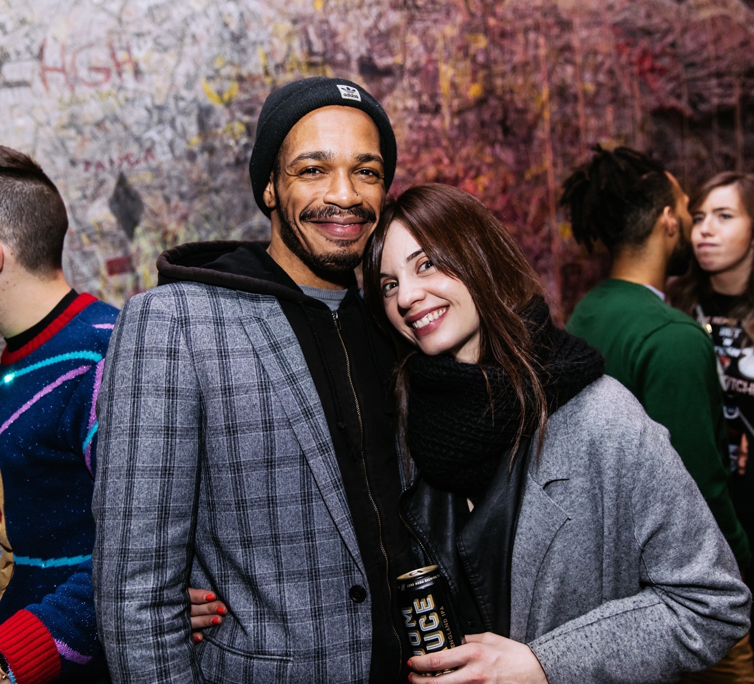 Two people in jackets smiling for photo in crowd