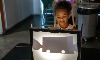 A child looks at a shadow in a box