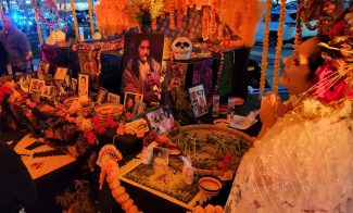 Decorated day of the dead altars with a woman in ceremonial costume