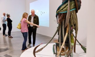 Two adults looking at a tall sculpture in a gallery