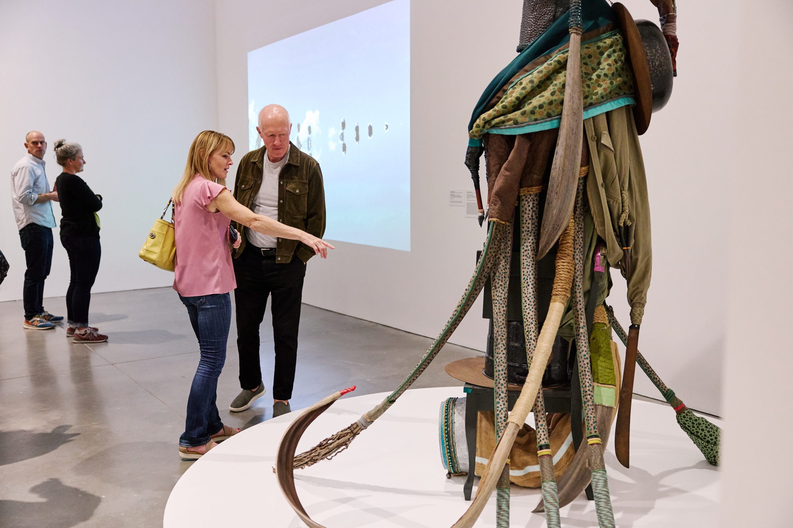 Two adults looking at a tall sculpture in a gallery