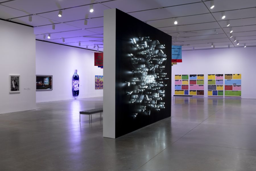 Gallery of artwork with black wall with white lights installed diagonally in foreground