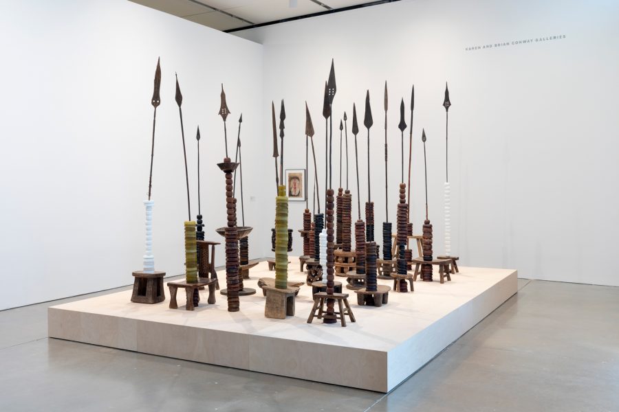 Sculpture installation of rows of spears on stools with different circular discs adorning them