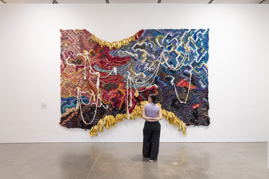 Person in purple top looking at blue and red tapestry