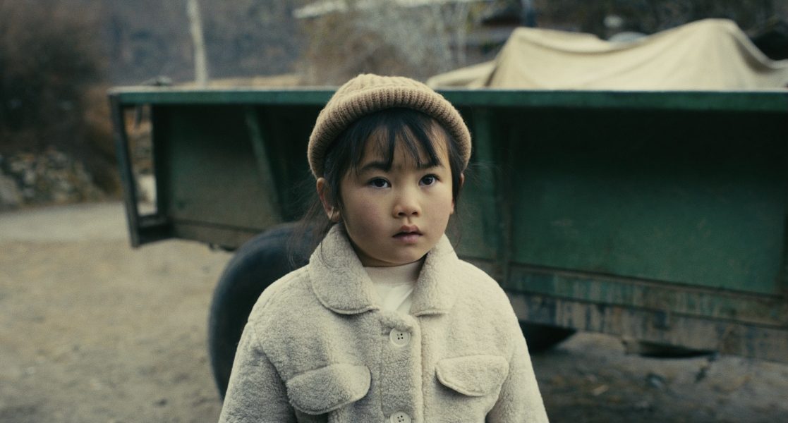 An Asian child in a white fleece jacket outside