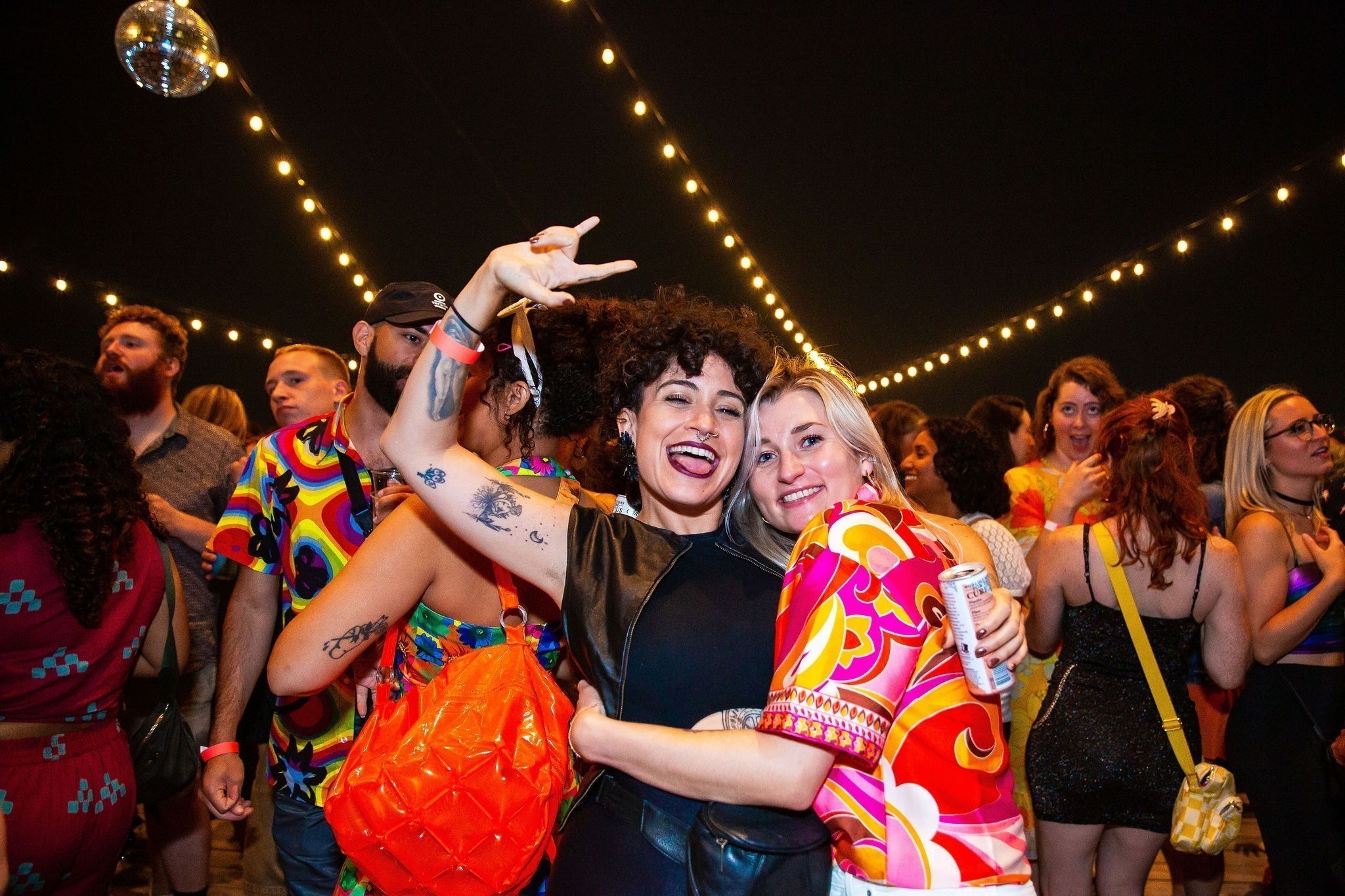 Two people pose for the camera amongst the crowd outdoors