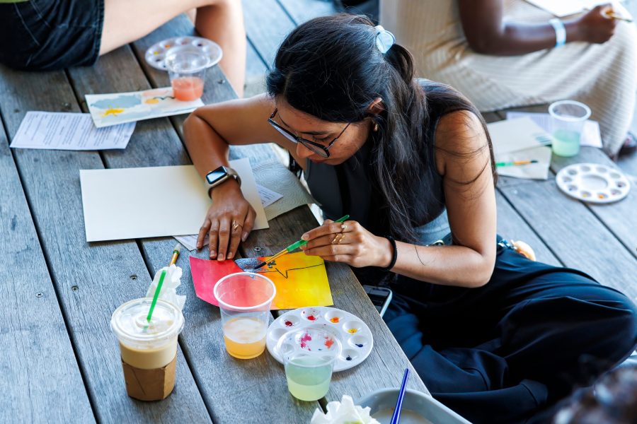 A person paints on paper with watercolors at an outdoor watercolor workshop.