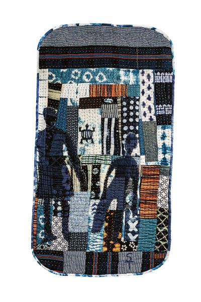 A rectangular, patchwork textile artwork featured at AAMARP, with various patterned fabric strips in blue, brown, and white tones, two dark silhouetted human figures, and a small hand-drawn crab motif on a lighter background.