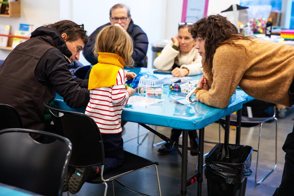 Adults and a child engaging in an activity at a blue table
