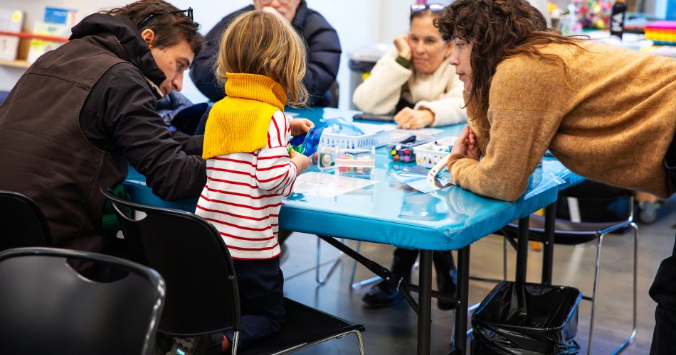 Adults and a child engaging in an activity at a blue table