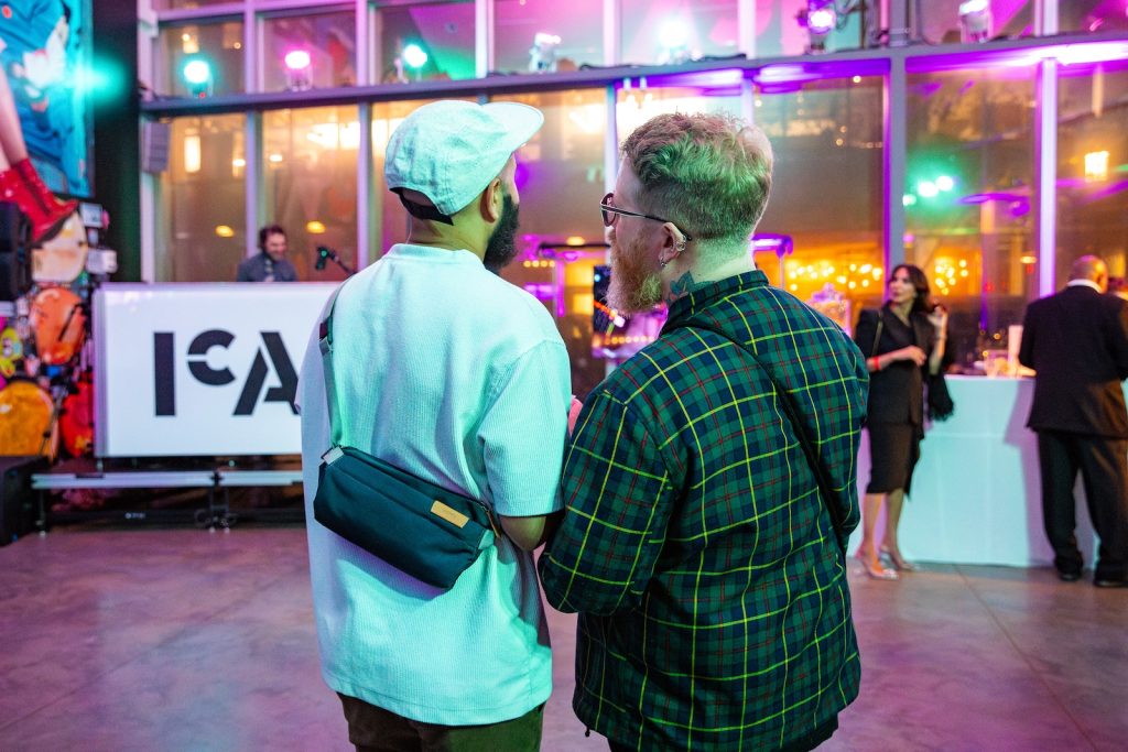 Two people stand indoors at the ICA and talking.