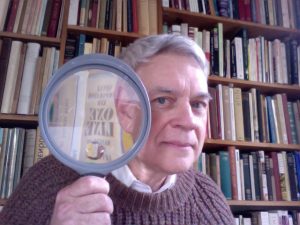 A headshot of a man holding a magnifying glass.