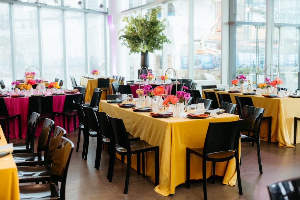 Tables set with decor and vibrant table clothes fill the Lobby of the ICA