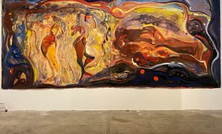 A large abstract painting with swirling, flowing shapes and vibrant colors, including yellows, reds, blues, and browns, displayed on a white gallery wall with a concrete floor beneath.