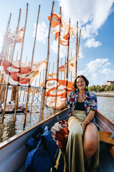 crystal bi sits on a boat next to a floating sculpture