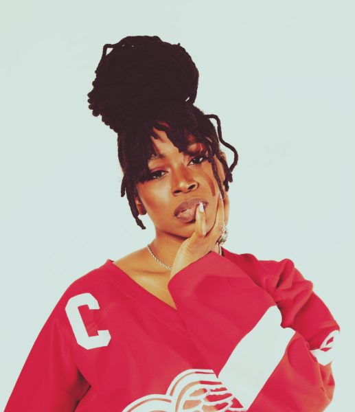 A woman in a red hockey jersey with a C on it poses with her hand near her face.