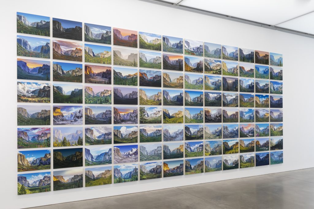 A white gallery wall displays a grid of landscape photographs, each showing a scenic mountain view in different lighting and seasons. The images are arranged in neat, horizontal and vertical rows.