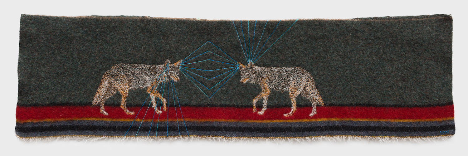 Two embroidered coyotes face each other on a dark, multicolored fabric panel with blue geometric lines connecting their eyes. The panel has red, yellow, and blue stripes at the bottom.