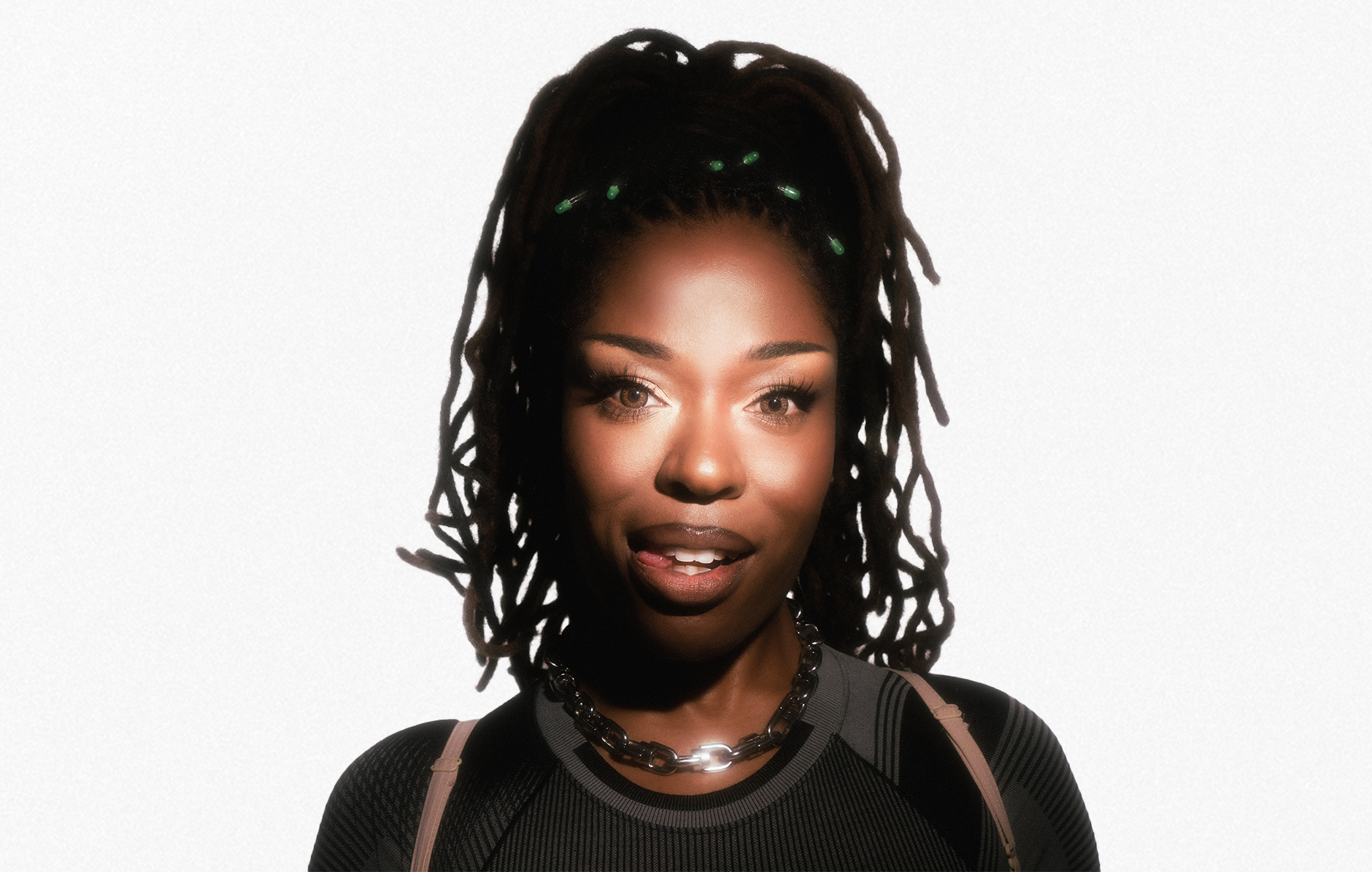 A woman smiles softly against a white background, lit dramatically from the front.