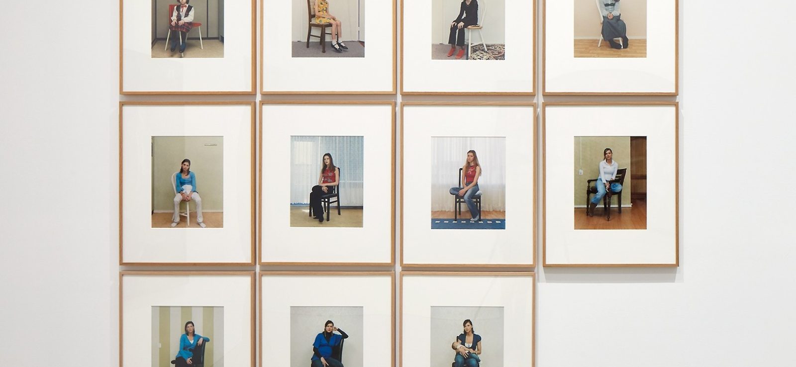 Eleven framed portraits of a woman sitting on a chair, arranged in a grid on a white wall.